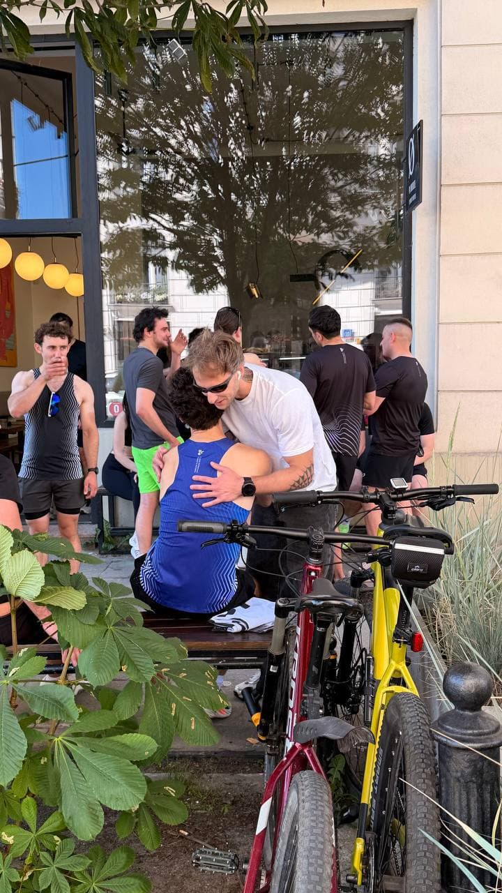 Runners hugging outside a café after a session, bikes parked nearby