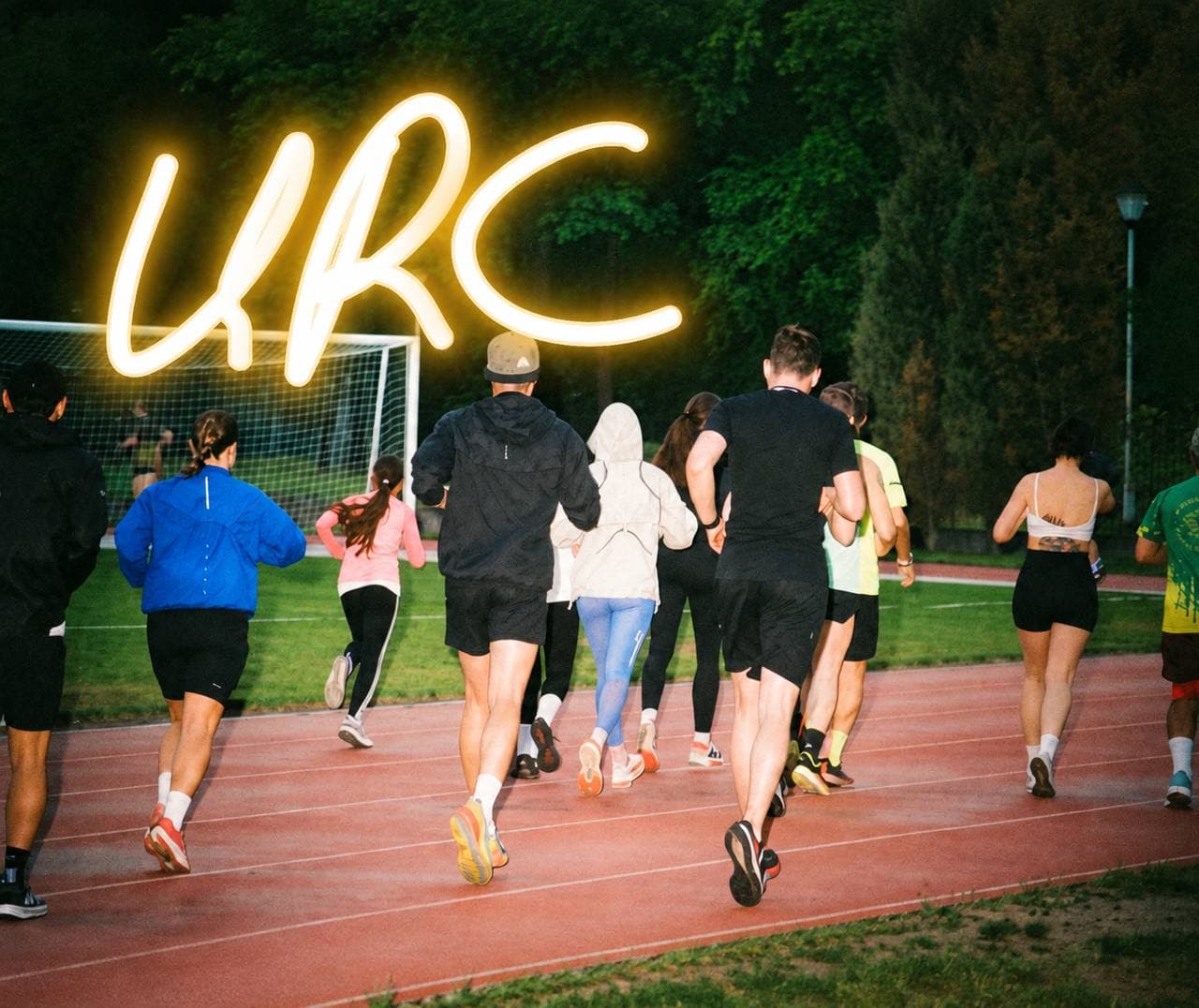 URC Warsaw runners on a track at dusk under a glowing URC sign