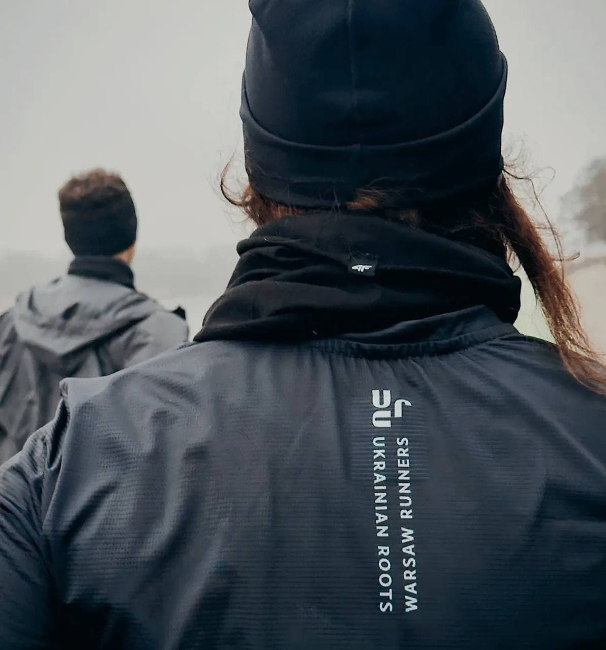 Runner in a Warsaw Runners jacket looking out over a misty lake