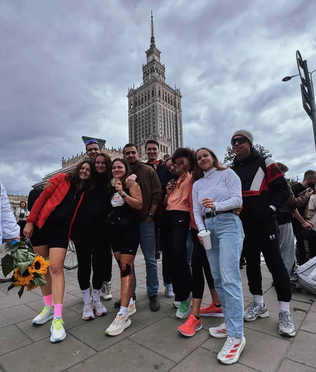 URC Warsaw runners celebrating together in front of the Palace of Culture