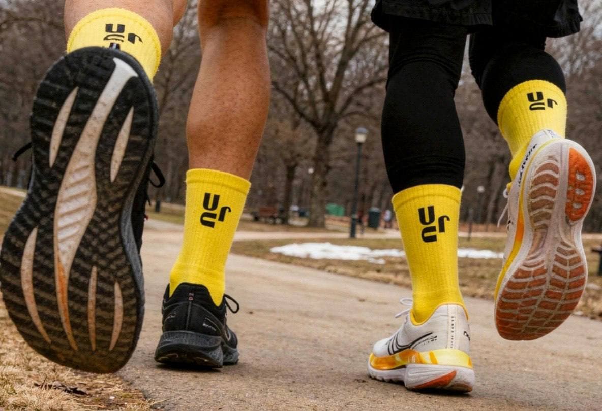 Two runners wearing yellow URC socks in a park